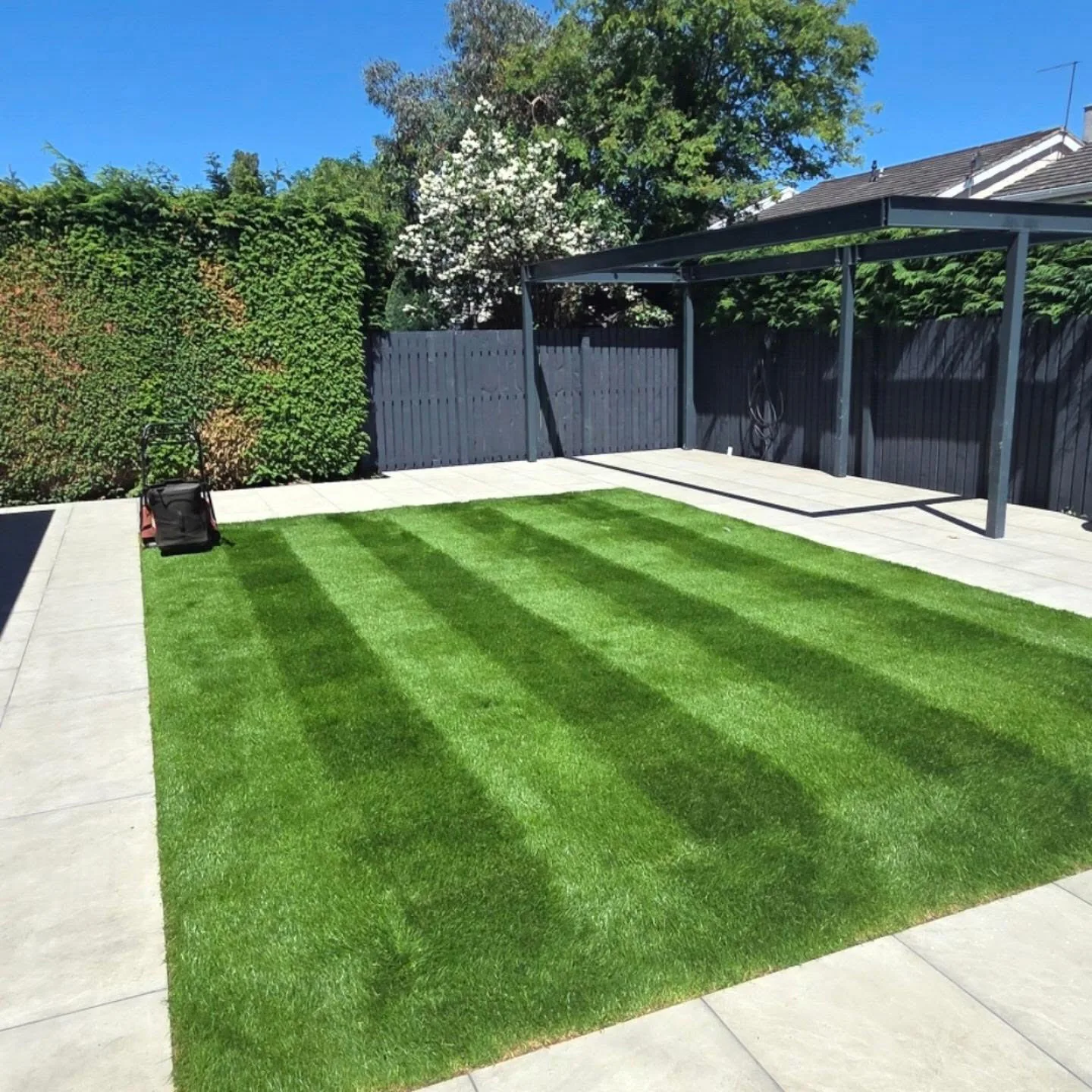 Striped lawn bordered by a light stone patio