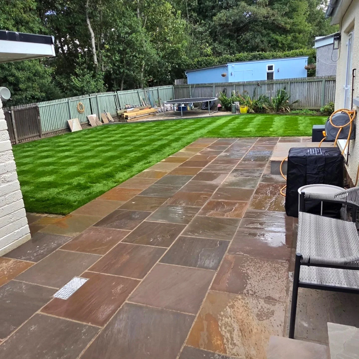 Patio and striped lawn in a landscaped back garden