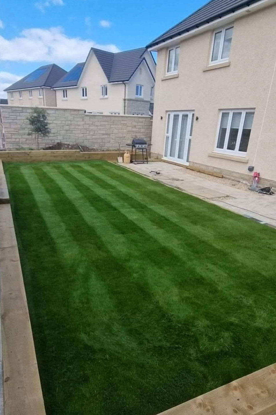 Established striped lawn running to a patio
